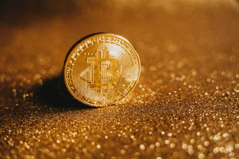 Detailed close-up of a Bitcoin on a glittery gold background, symbolizing digital finance.